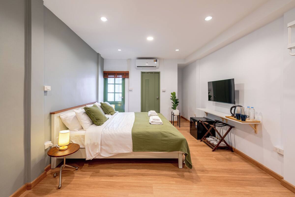 A neatly arranged bedroom with a bed, bedside table, and a TV on a stand.