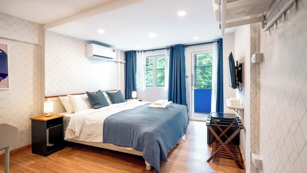 A modern bedroom with a bed, bedside table, and a small desk with a chair. - Bluehouse191 hometel (Bangkok)
