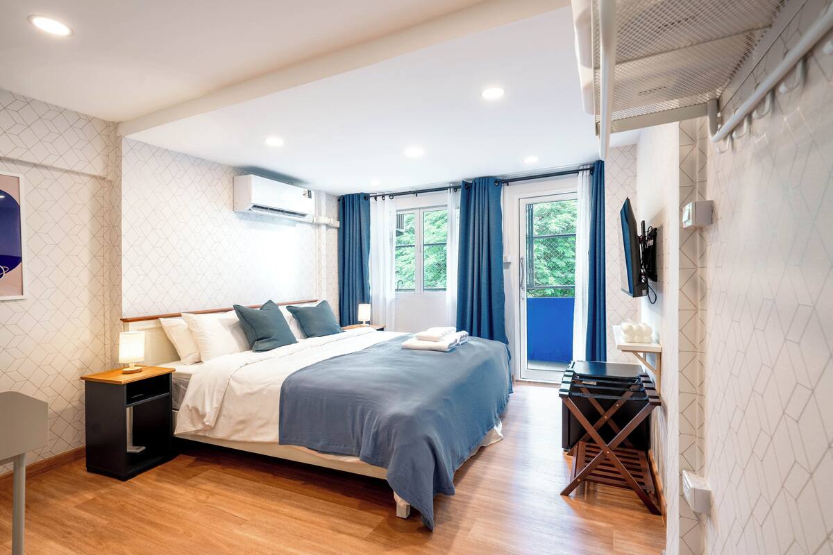 A modern bedroom with a bed, bedside table, and a small desk with a chair.