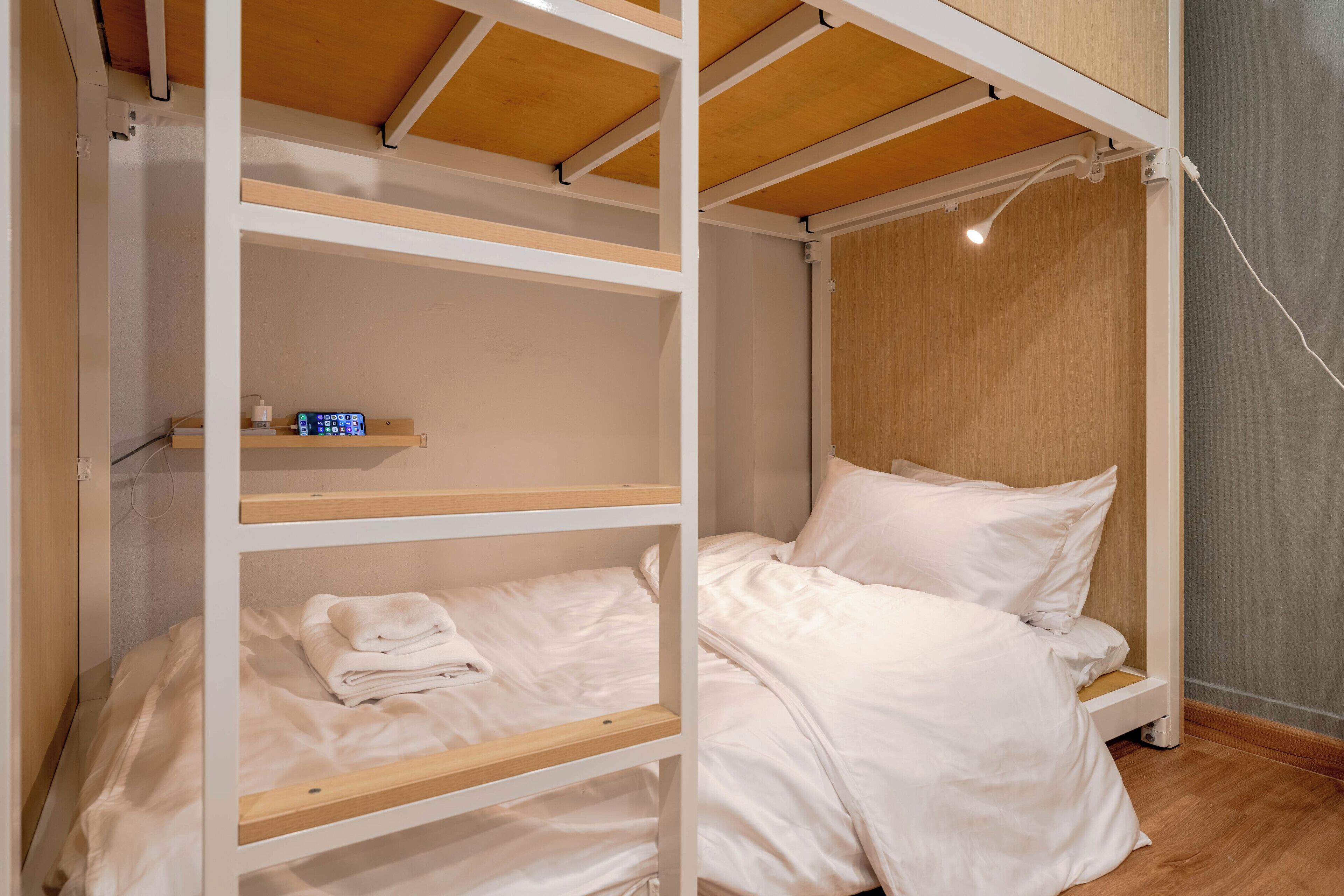 Dormitorio con literas, techo de madera, repisa con un reloj y mesita de noche.