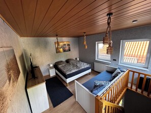 A bedroom with a bed, bedside table, lamp, window, and a view of the outside. - Cozy vacation home in the heart of Cuxhaven (Cuxhaven)