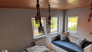 A room with a bed, a daybed, and a window with a view of greenery. - Cozy vacation home in the heart of Cuxhaven (Cuxhaven)