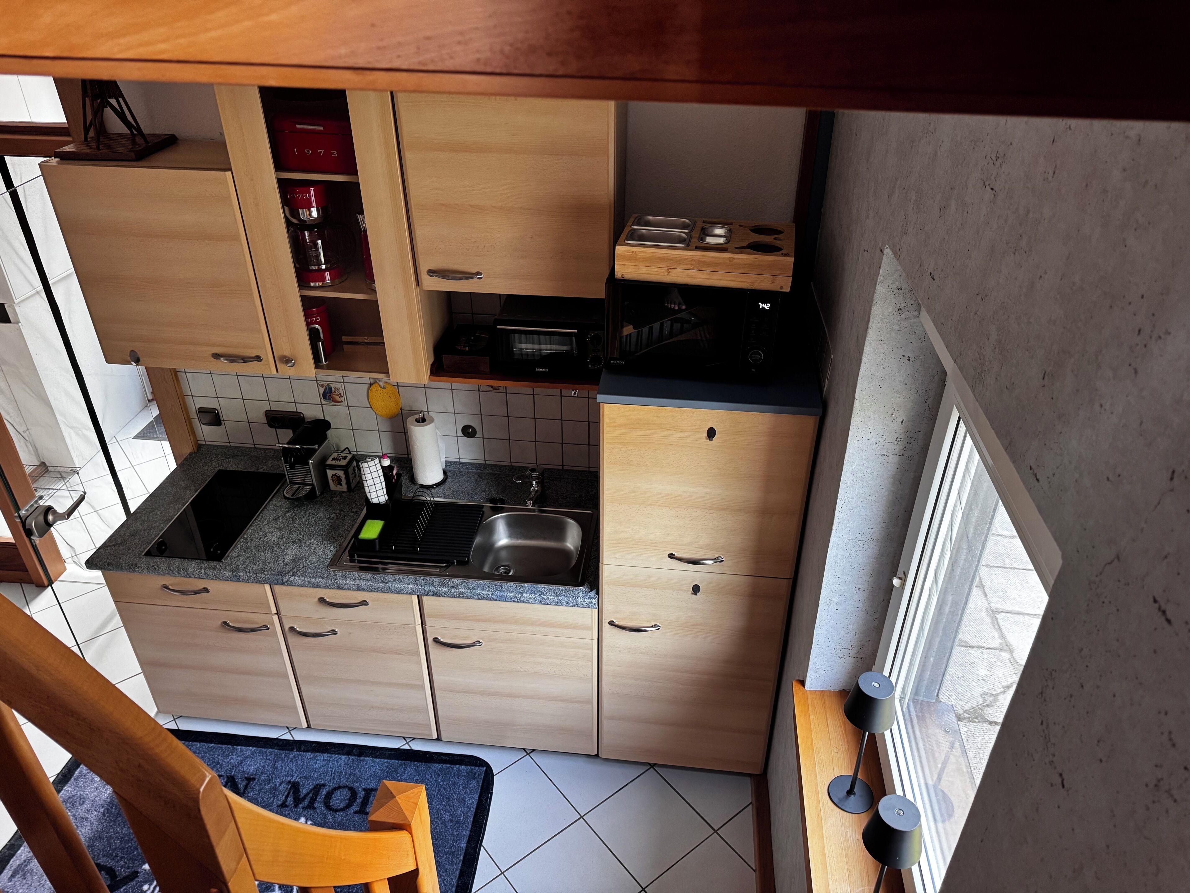 Eine kleine Küche mit Holzausstattung, einer eingebauten Mikrowelle und einem Spülbecken.