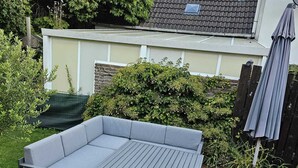 Un patio con un sofá seccional gris, dos bancos iguales y una mesita.