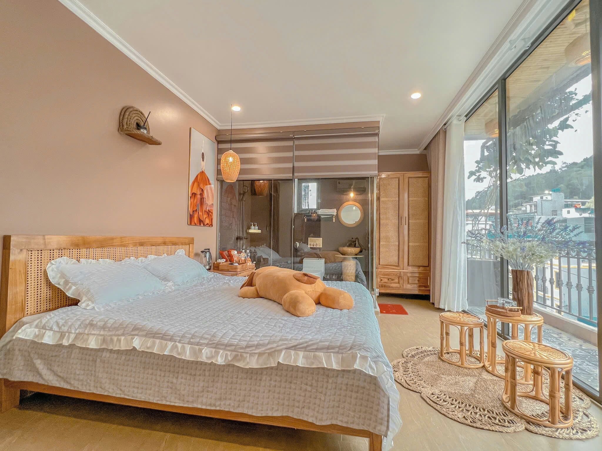 A bedroom with a large bed, a wardrobe, a bathroom with a glass door, and a view of the city.