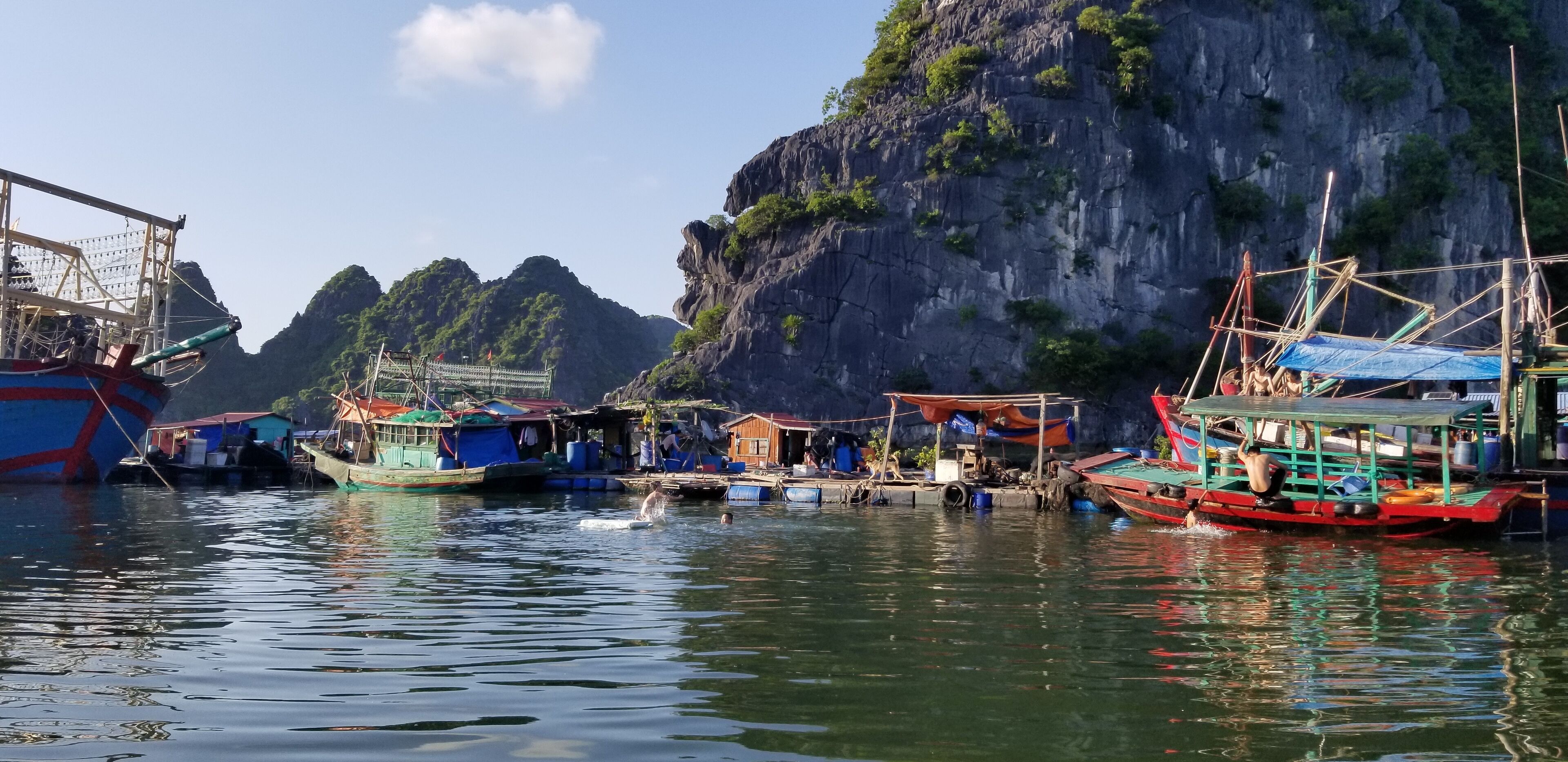 Paisaje costero con barcos amarrados cerca de un acantilado.