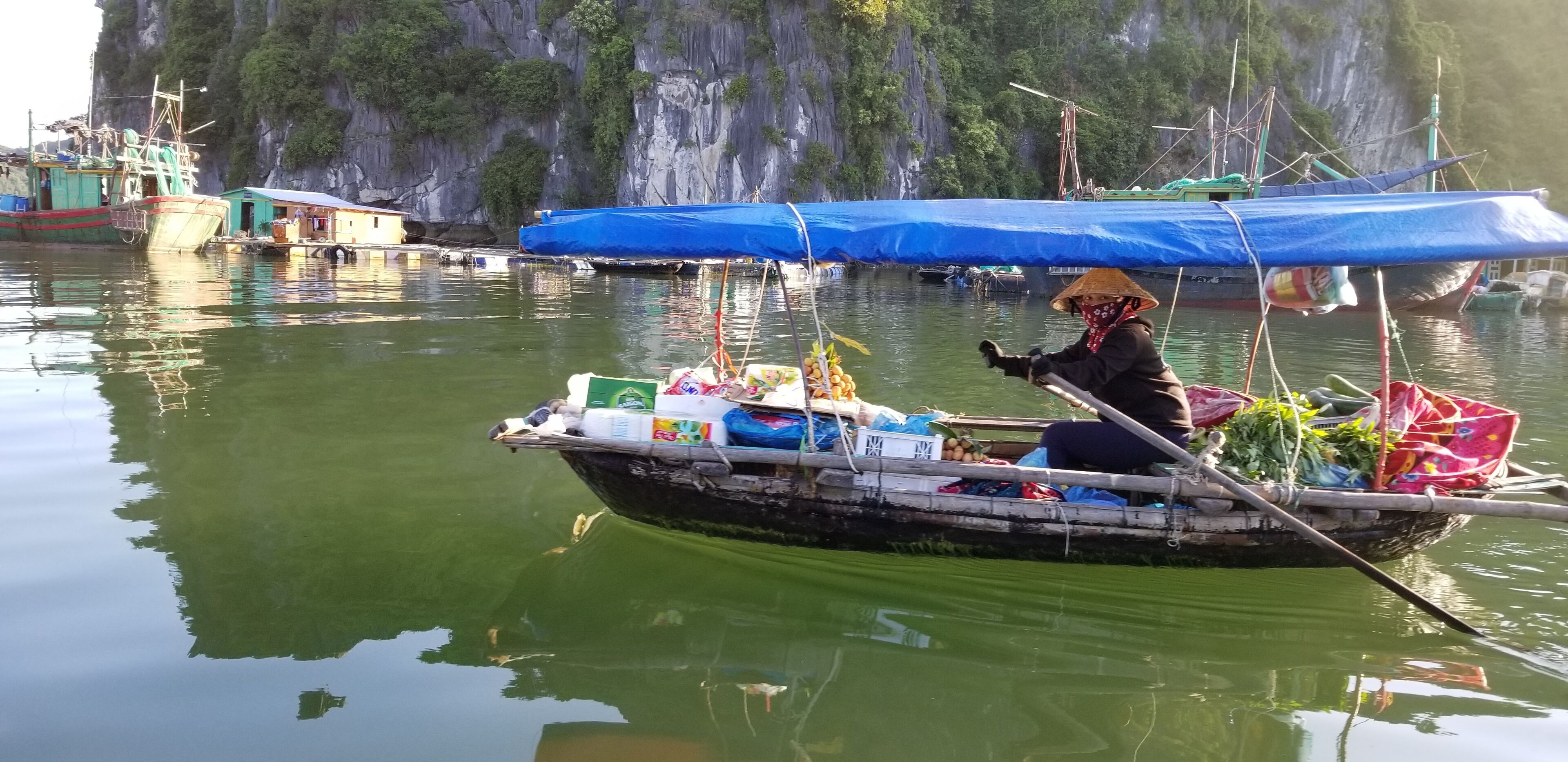 Una embarcación con diversos objetos a bordo, incluyendo bolsas y contenedores, flotando sobre aguas tranquilas.