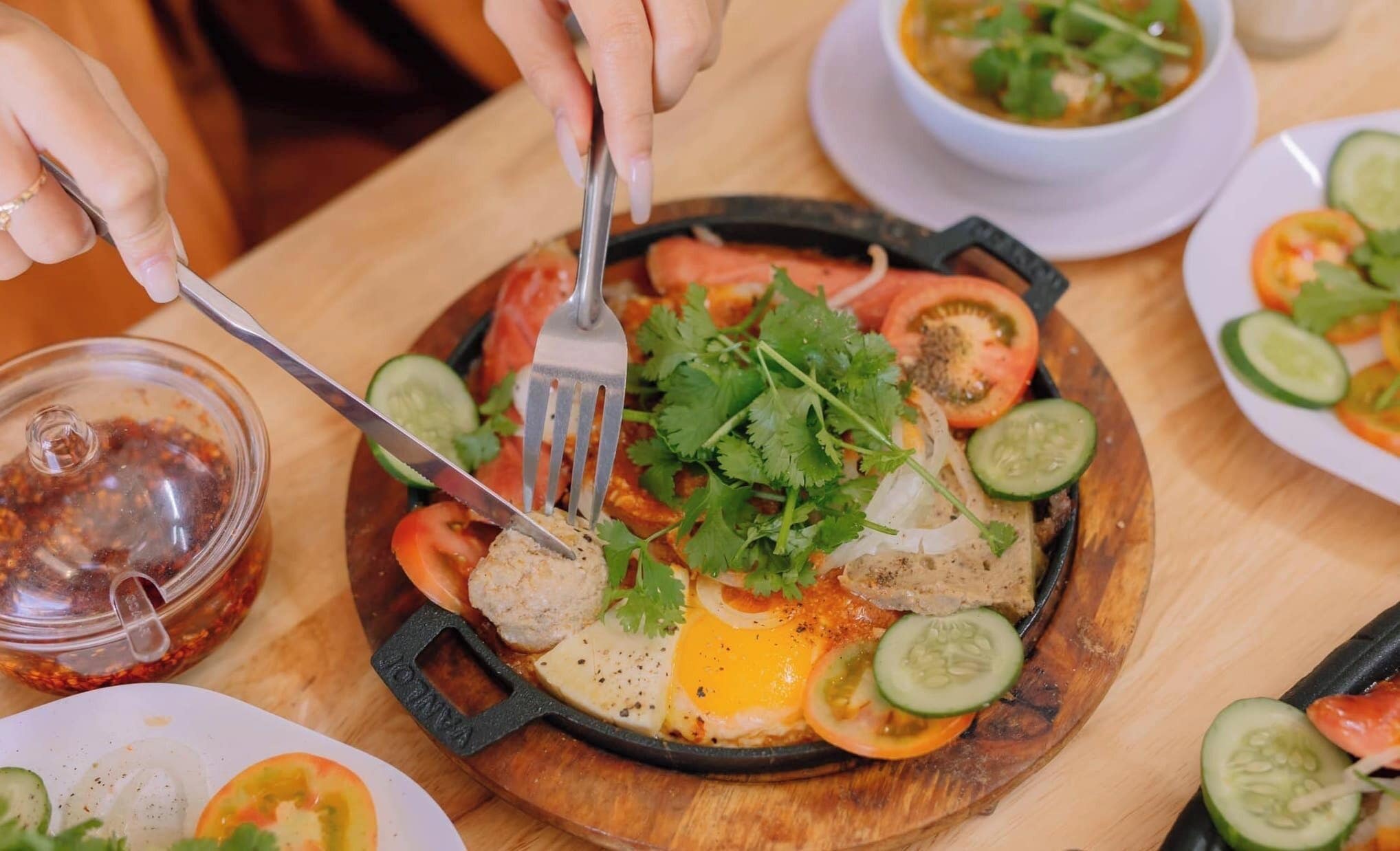 Un plato con diversas verduras y un huevo frito sobre una tabla de madera.