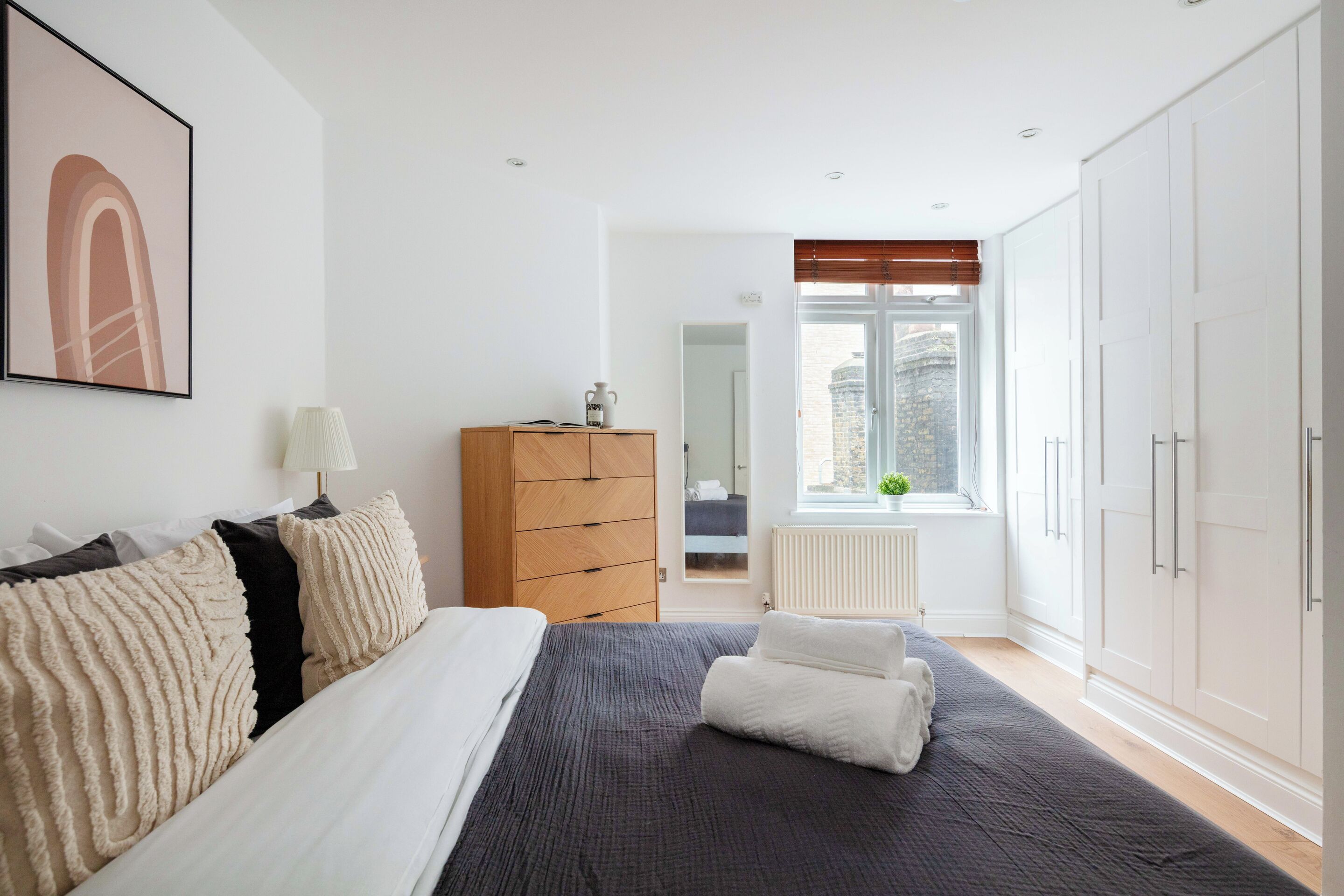 Quarto com cama, cômoda, janela e radiador.