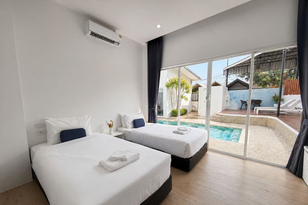 A hotel room with two beds, a pool, and a view of the outside.