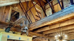 A rustic wooden interior with exposed beams, a stone wall, and a unique ceiling light fixture. - LE GÎTE DU BOIS DE L'HIVER, large character property at the foot of the Puy-de-Dôme mountains (Ceyssat)