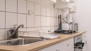 A modern kitchen with white tiles, stainless steel appliances, and a wooden countertop.