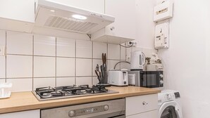A modern kitchen with a gas stove, toaster, microwave, and a washing machine.