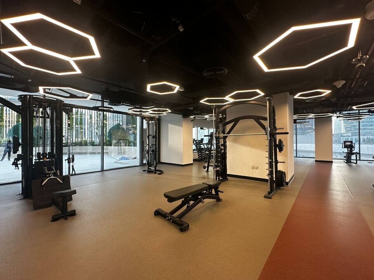 Ein Fitnessstudio mit Trainingsgeräten, Bänken und einem großen Fenster.