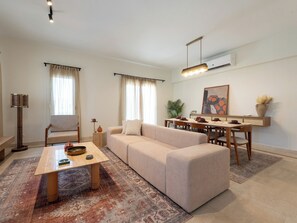 A modern living room with a sofa, coffee table, and dining area. - BirdNest - Mivida New Cairo (New Cairo)