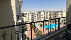 Ένα μπαλκόνι με θέα σε μια πισίνα που περιβάλλεται από κτίρια.