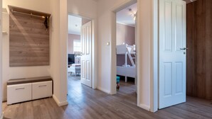 A hallway with a wooden floor, a bench, and a door leading to a room with a bunk bed. - Ferienwohnung in St. Peter-ording (St. Peter-Ording)