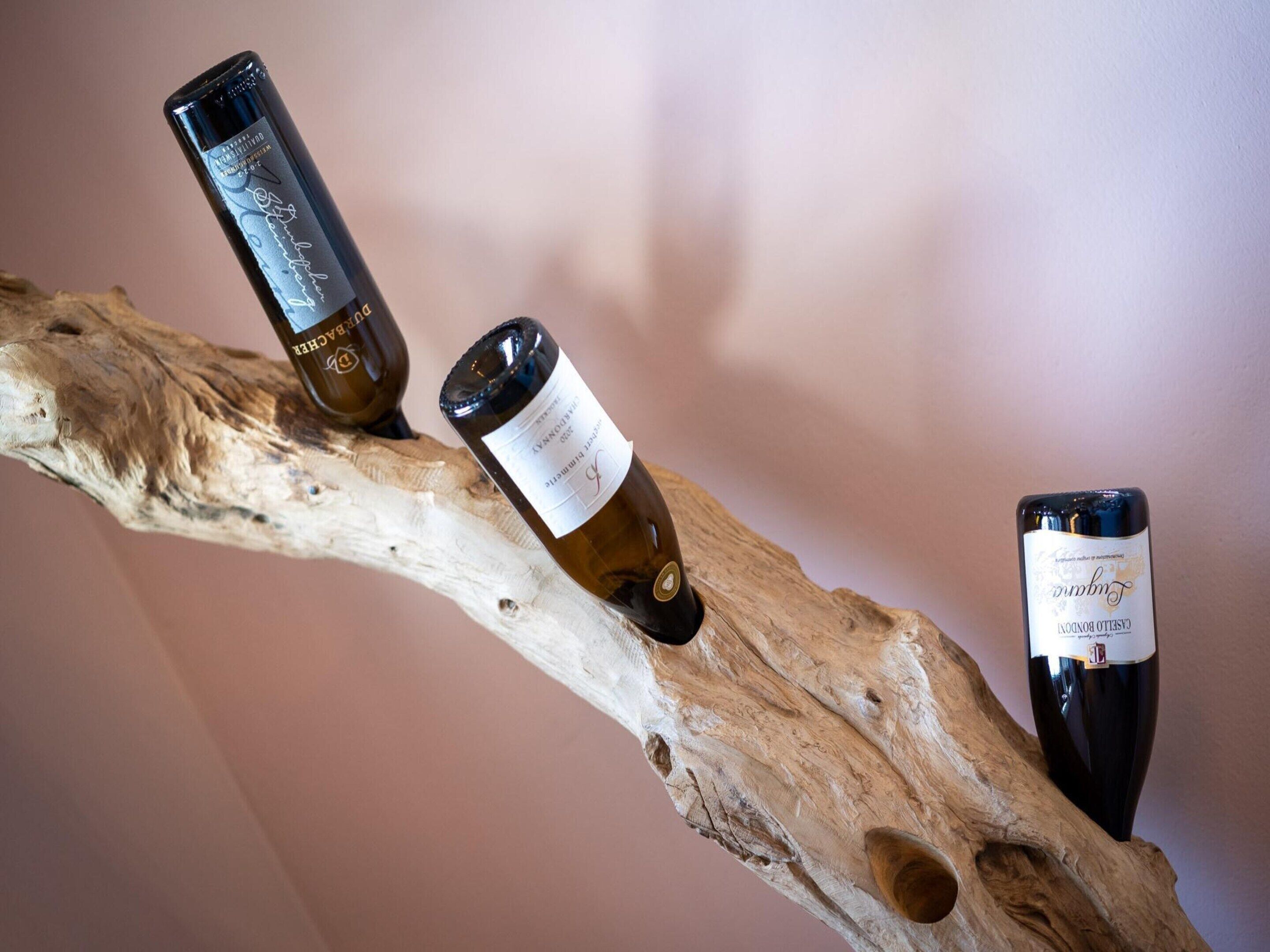 Three wine bottles on a branch.