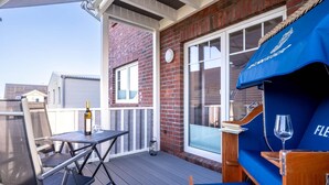 A covered outdoor patio with a table, chairs, a grill, and a wine glass. - Ferienwohnung in St. Peter-ording (St. Peter-Ording)