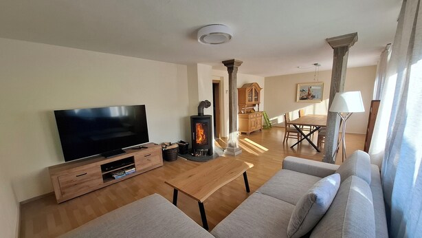 Una sala de estar con televisión, sofá, mesa de centro de madera y chimenea.