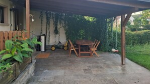 Un patio cubierto con una mesa, sillas, una bicicleta y un cerco de madera.
