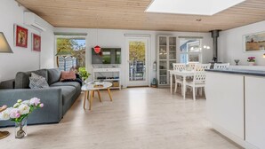 A modern living room with a grey sofa, a small round table, and a white dining area with chairs. - "Einari" - 500m from the sea by Interhome (Rødby)