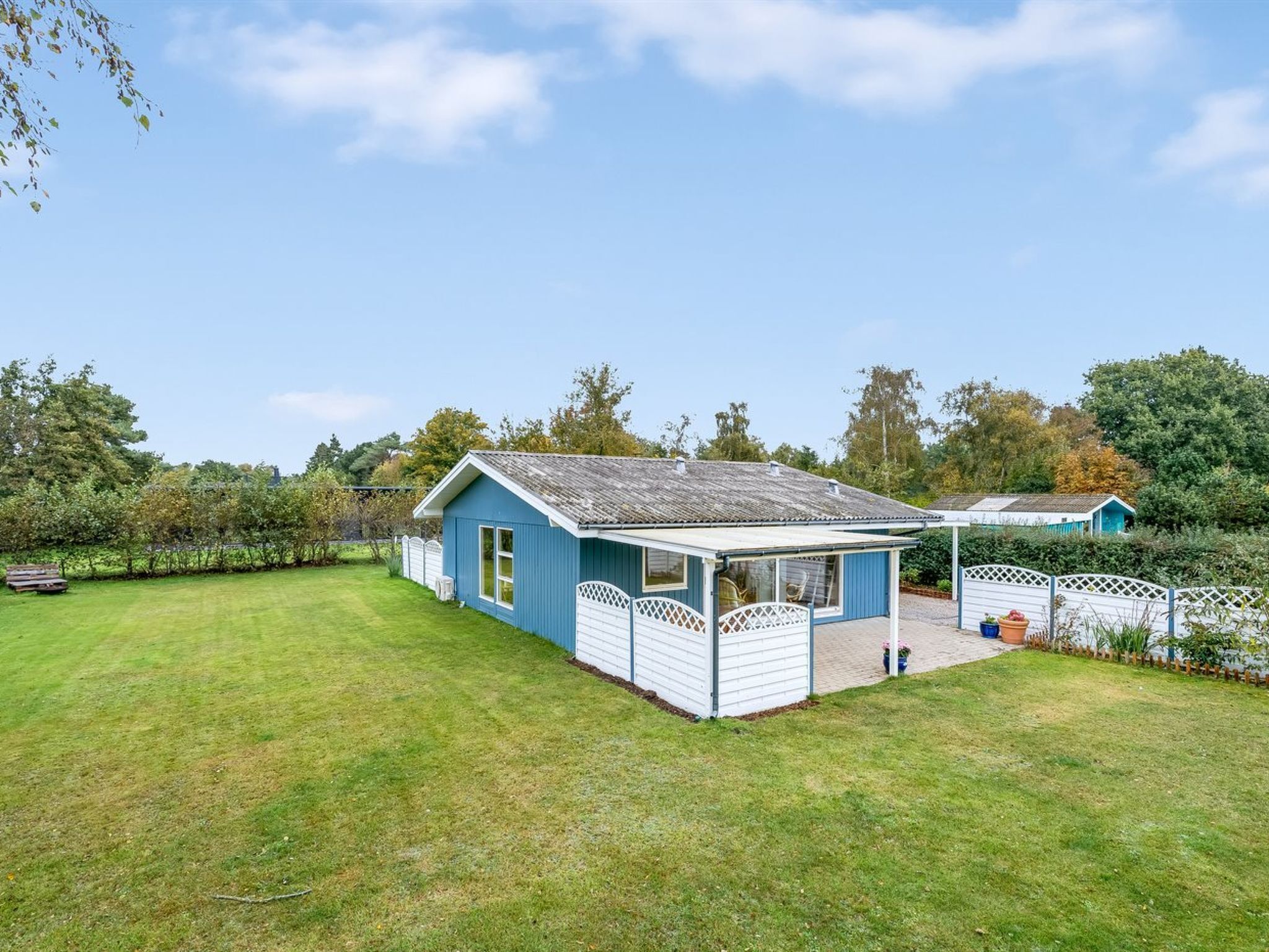 A blue house with a white porch and a fenced yard.