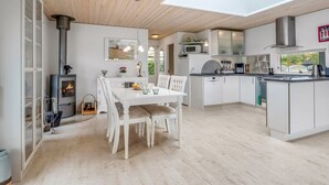 A modern kitchen with white cabinetry, a central island, and a skylight above the dining area. - "Einari" - 500m from the sea by Interhome (Rødby)