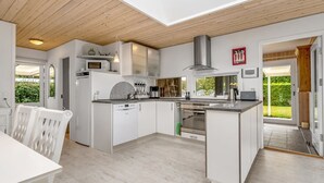 A modern kitchen with white cabinetry, a built-in oven, and a large island. - "Einari" - 500m from the sea by Interhome (Rødby)