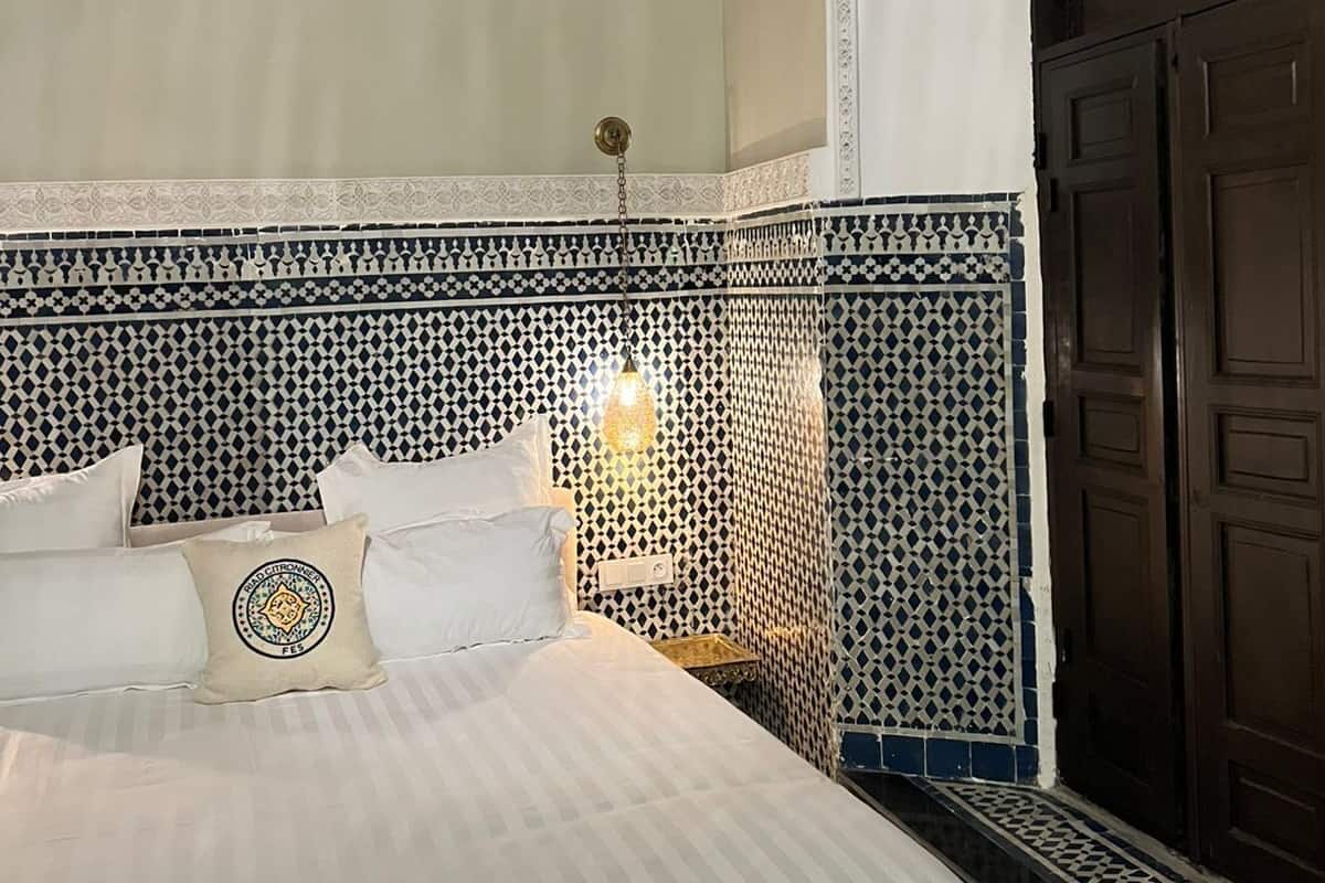 Un dormitorio con cama, mesita de noche, aire acondicionado instalado en la pared y techo decorativo.