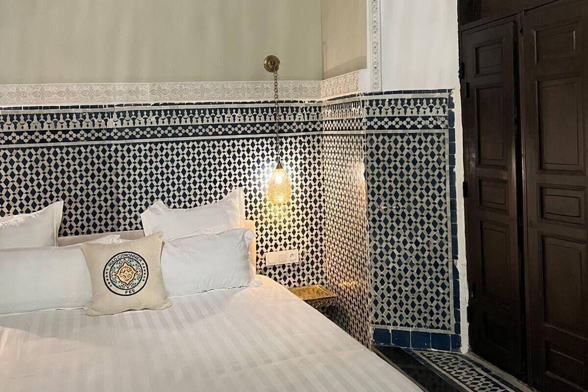 Una habitación de hotel con una cama, un detalle decorativo en la pared, una puerta y un equipo de aire acondicionado.