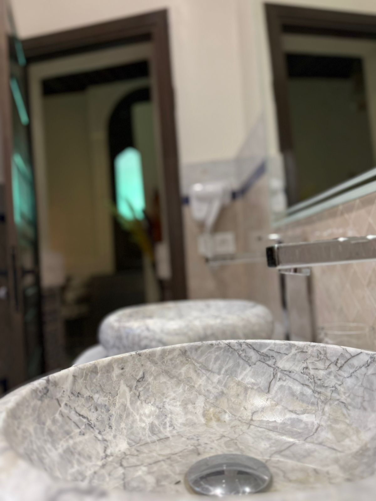 A bathroom with a marble sink, a glass shower enclosure, and a mirror.