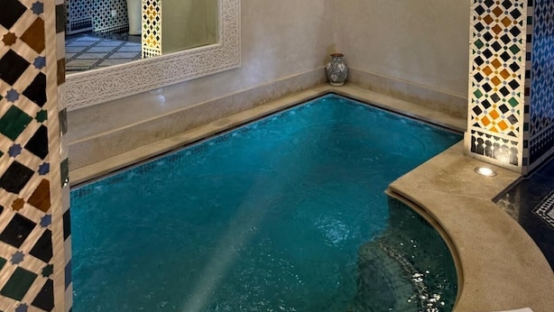 A swimming pool with intricate tile work and a decorative ceiling. - Riad citronnier (Fès)