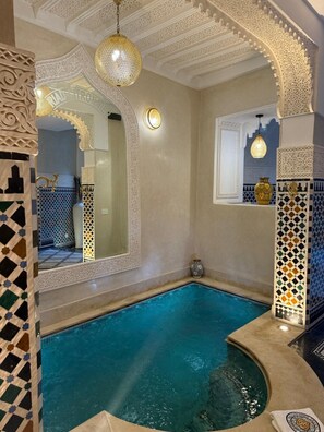 A swimming pool with intricate tile work and a decorative ceiling. - Riad citronnier (Fès)