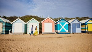 A row of beach huts with varying colors and designs, including a hut labeled "Bayside 58C".