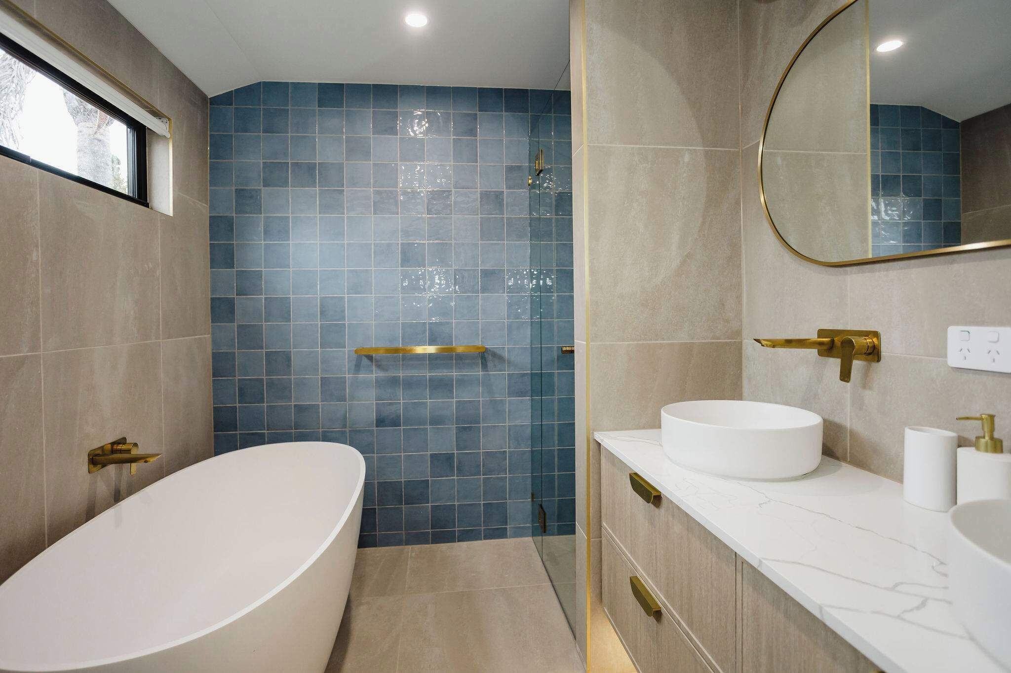 Une salle de bain moderne avec une baignoire sur pieds, une douche à parois de verre et un meuble-lavabo doté de deux vasques et d’un miroir.