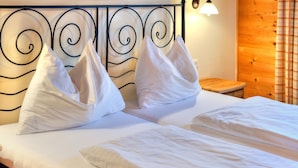 A bed with white linens and pillows, a wooden nightstand, and a metal headboard with a spiral design. - Feriendorf Wildschonau -cozy Escape (Wildschönau)
