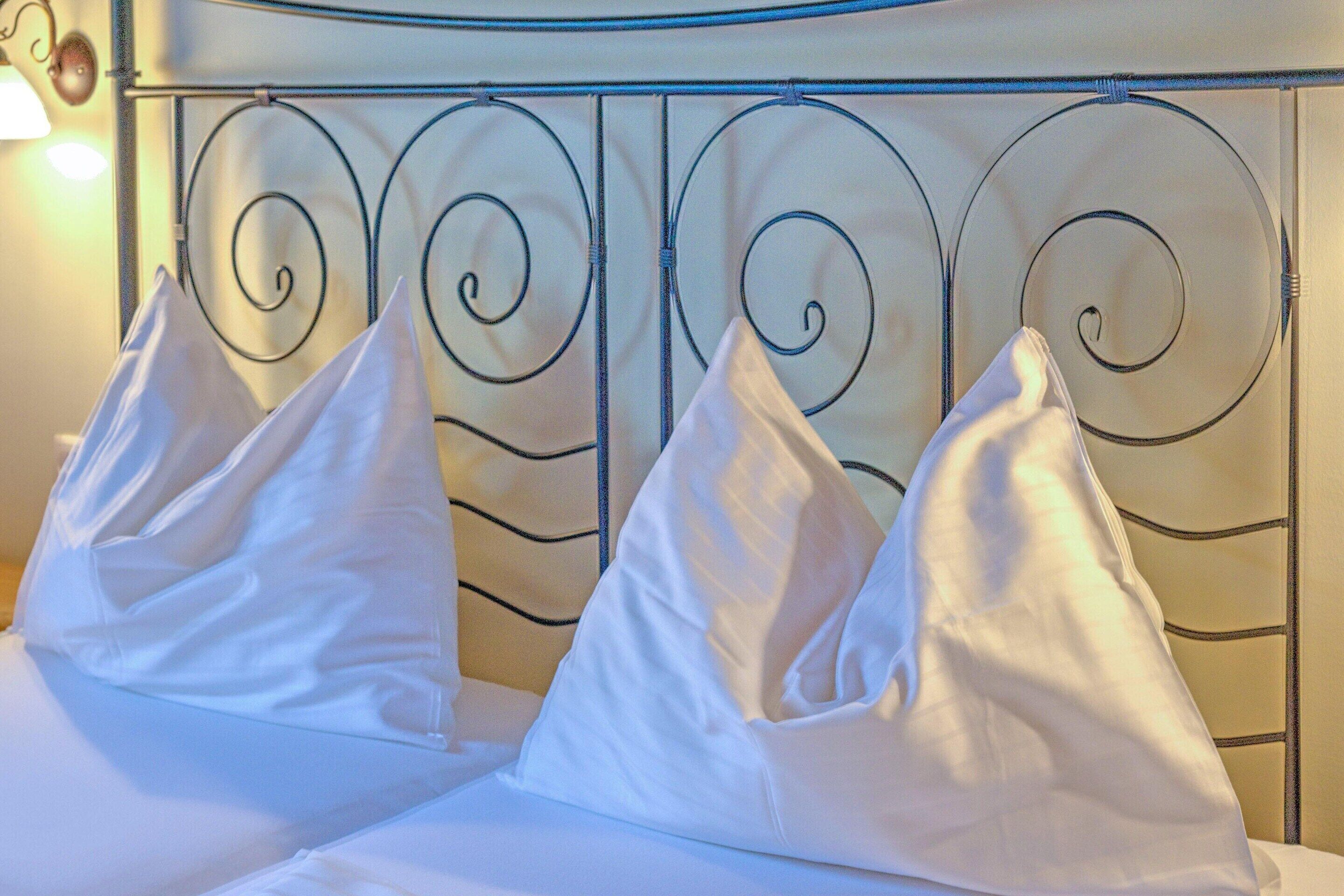 Una cama con cabecera de metal y almohadas blancas.