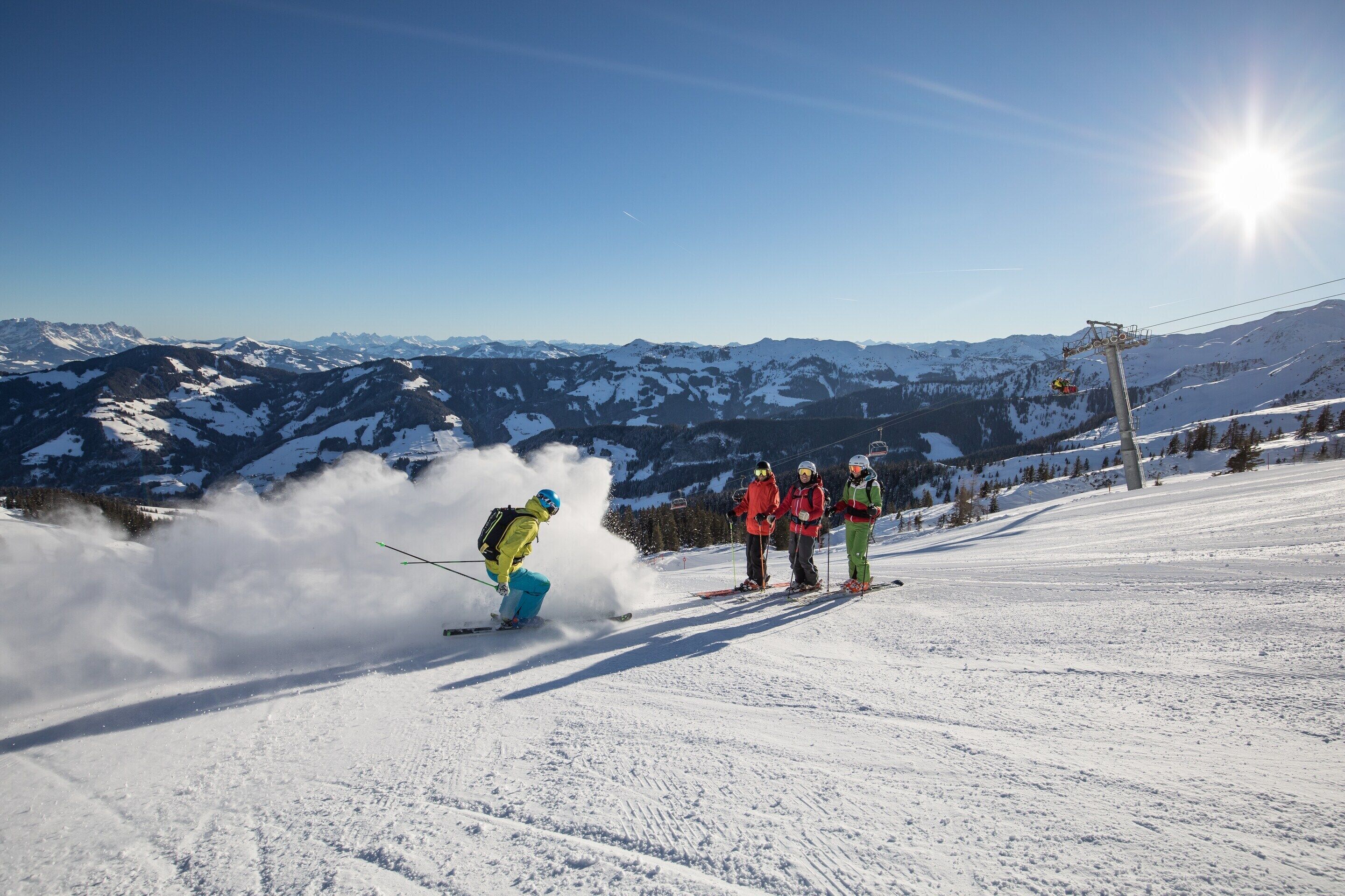 A snowy mountain slope with skiers, a ski lift, and a clear sky.