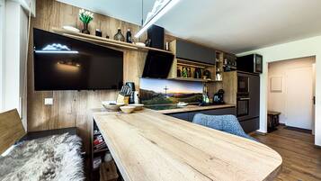 Eine moderne Küche mit Holztischplatte, integrierten Geräten und einem flachbildfernseher, der über der Arbeitsfläche angebracht ist.