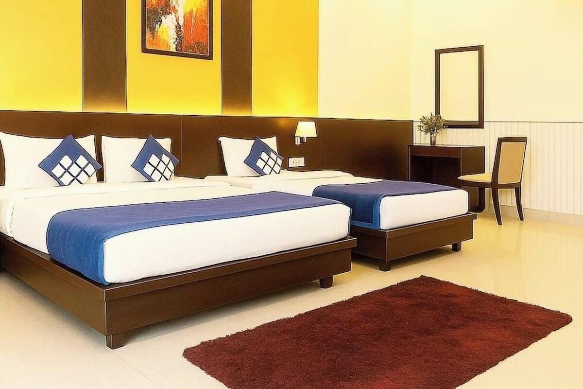 A hotel room with two beds, a large painting, a mirror, and a red rug.