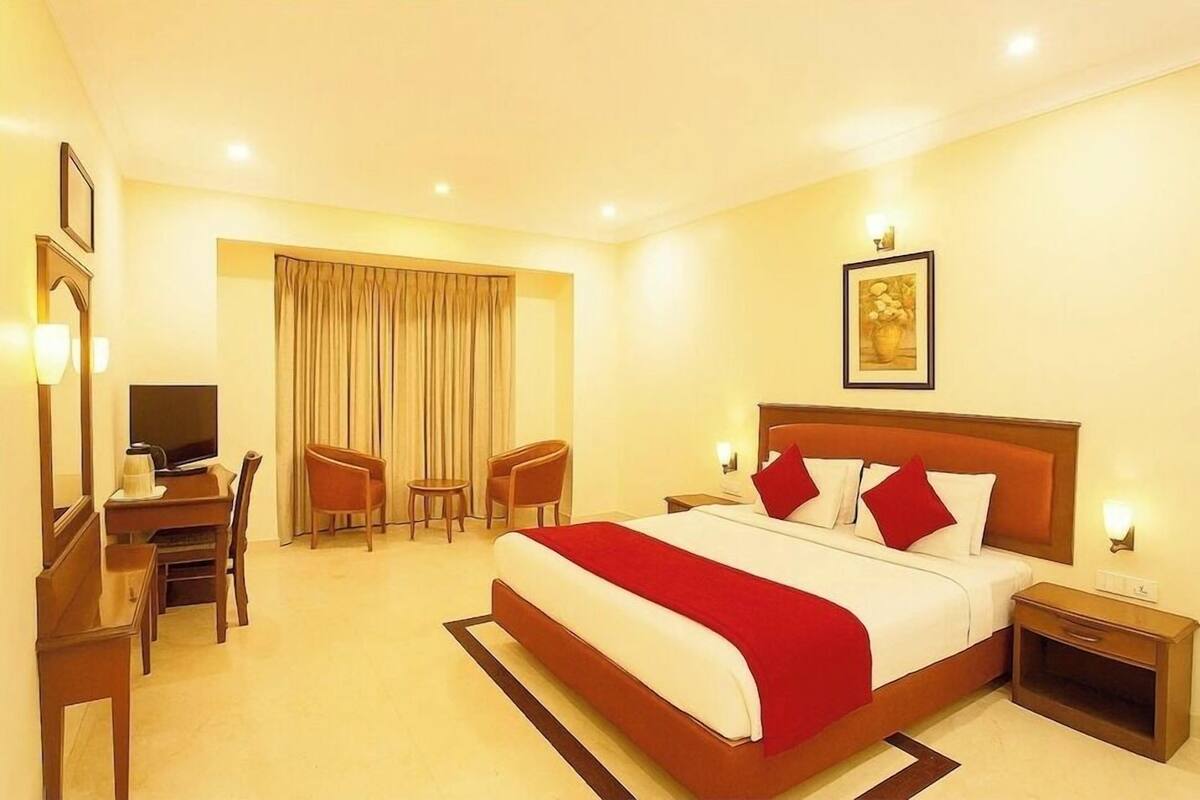 A hotel room with a bed, a desk, a TV, and a chair.