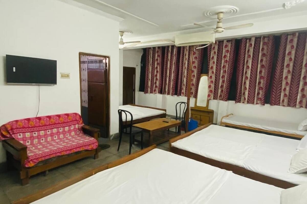 A room with two beds, a sofa, a desk, and a television.