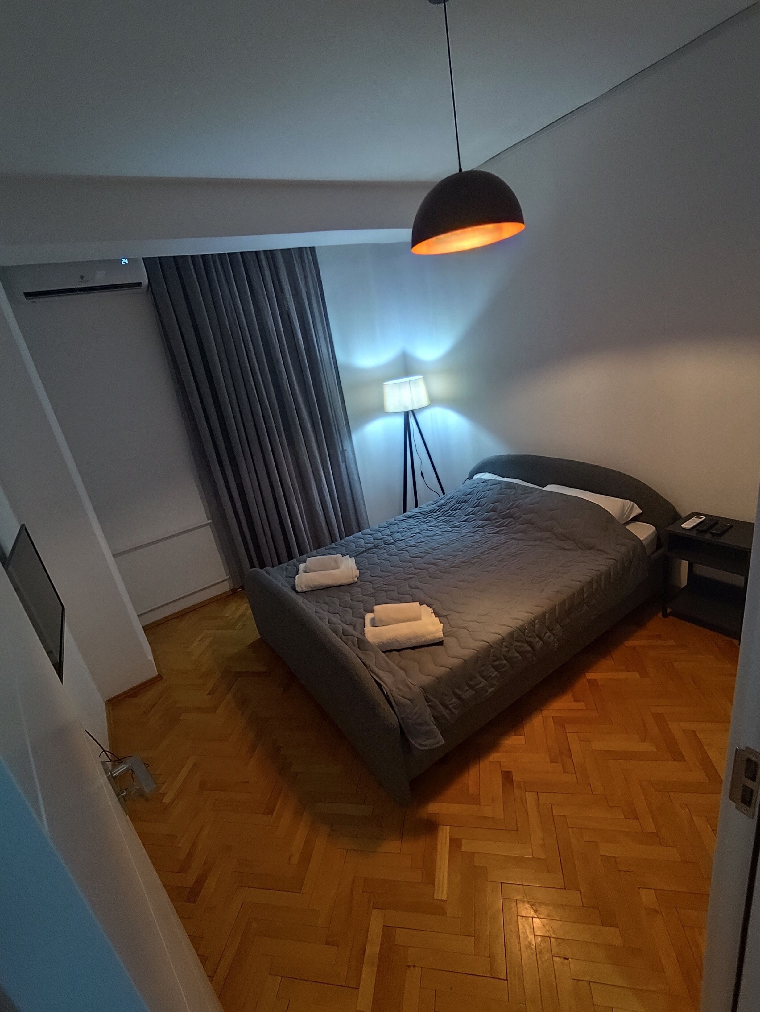 A bedroom with a bed, a standing lamp, and a ceiling fan.