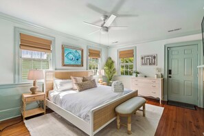 A bedroom with a bed, bedside tables, a bench, a dresser, and artwork on the walls.