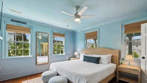 Ein Schlafzimmer mit einem Bett, zwei Nachttischen, einem Fenster mit Blick und einem Deckenventilator.