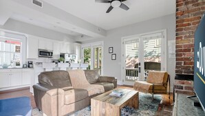 A modern living room with a leather sofa, a wooden coffee table, and a blue armchair. - The Queens Palace | 8 Bedrooms in Charleston! (Charleston)