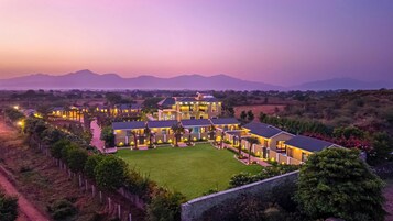 Um grande resort com vários edifícios, um gramado bem cuidado e vista para montanhas ao longe.