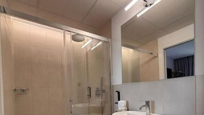 Une salle de bain moderne avec une douche à parois de verre, un lavabo blanc et un grand miroir.