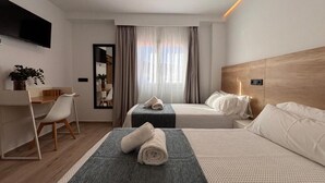 Une chambre d’hôtel moderne équipée de deux lits, d’un bureau et d’une télévision.